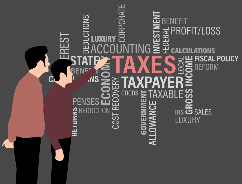 Cartoon rendering of two men discussing tax-related topics represented by financial/accounting terms displayed on a wall.