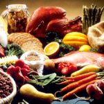 alt="a variety of healthy foods (proteins, vegetables, and grains) spread out on a table"
