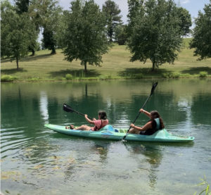 Click on this photo of youth in a kayak on a lake to learn about 4-H summer camps