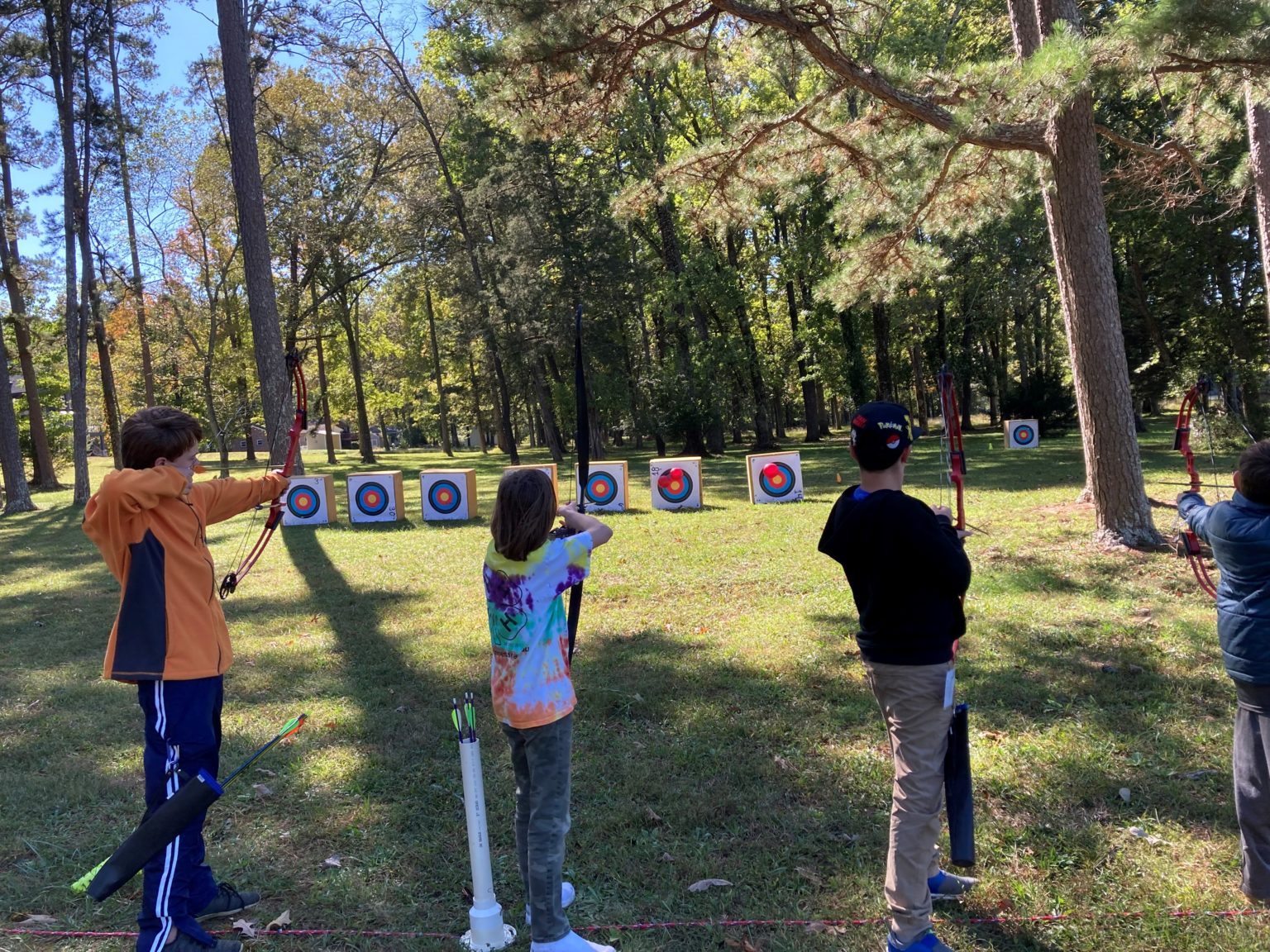 students practicing archery at a park