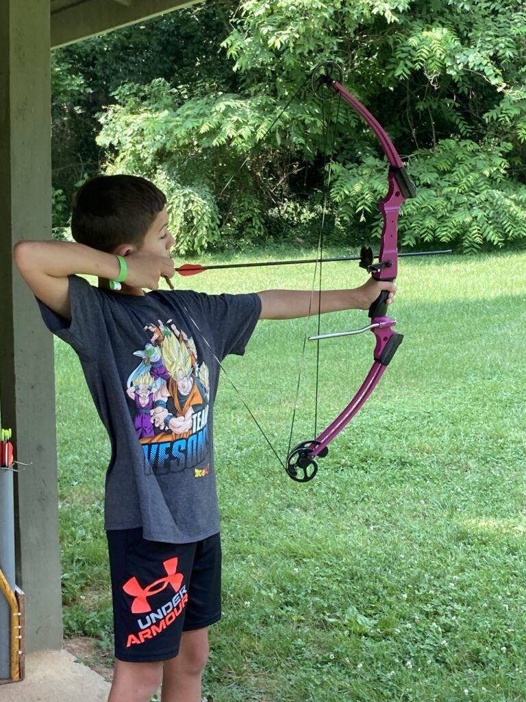boy shooting a bow at the archery range