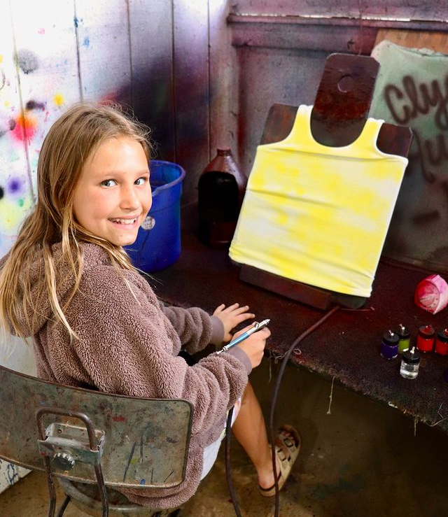 girl airbrushing a shirt at camp