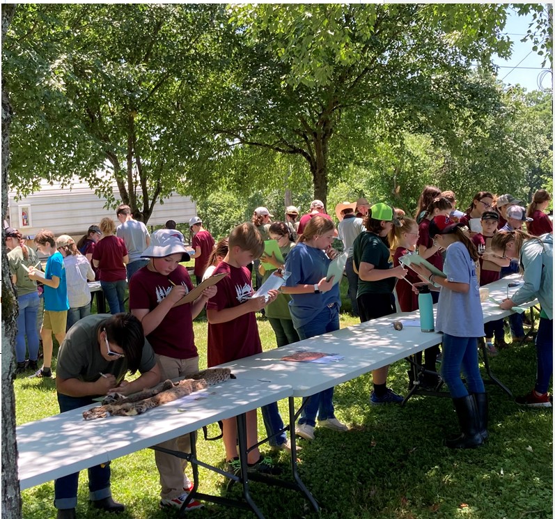 Children outside at a contest answering questions on paper