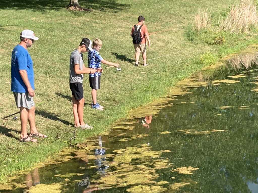 three teens fishing in a pond