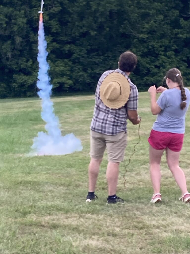 A bottle rocket shooting off as two people watch