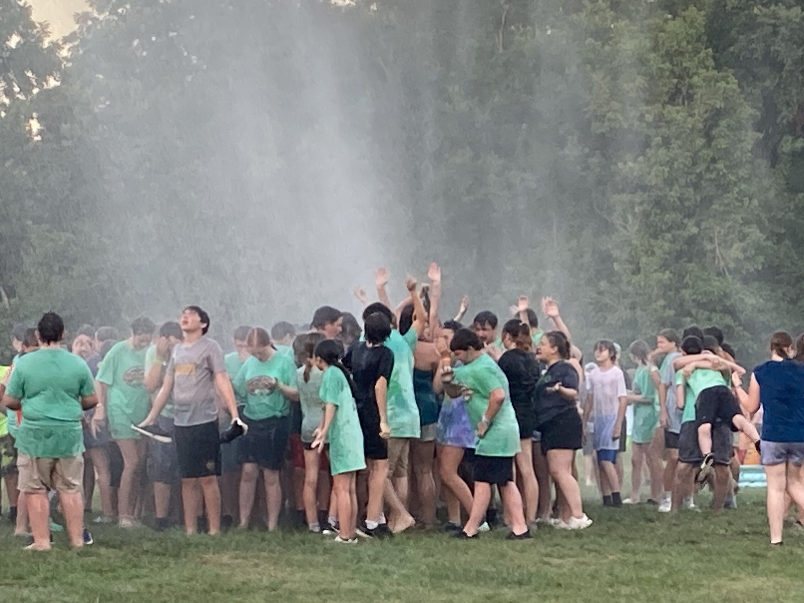 A group of teens stand under a water spray