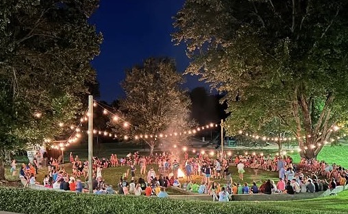 A campfire at camp with teens sitting around it