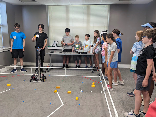 Photo of a boy driving a robot while other children and teens watch